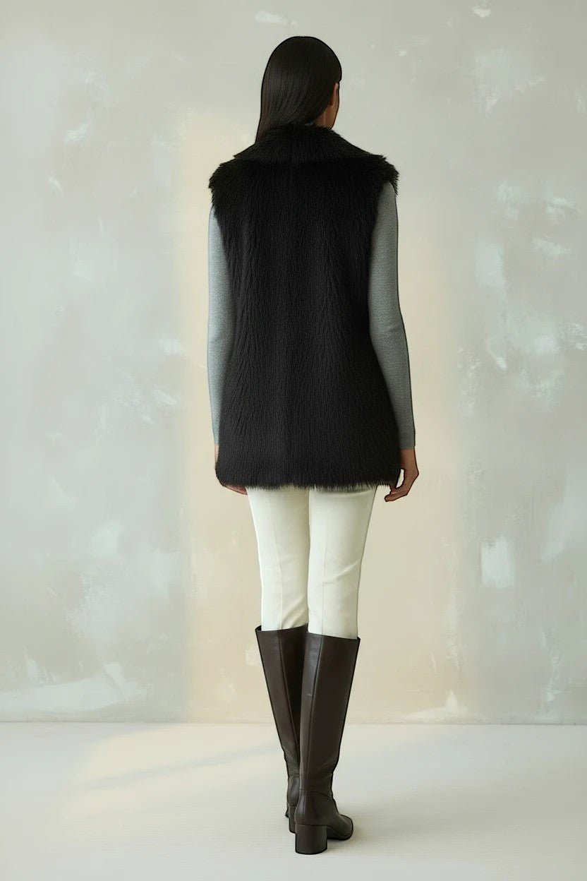 Refined Elegance black faux fur sleeveless vest worn over a grey long-sleeve top, white trousers, and brown boots.