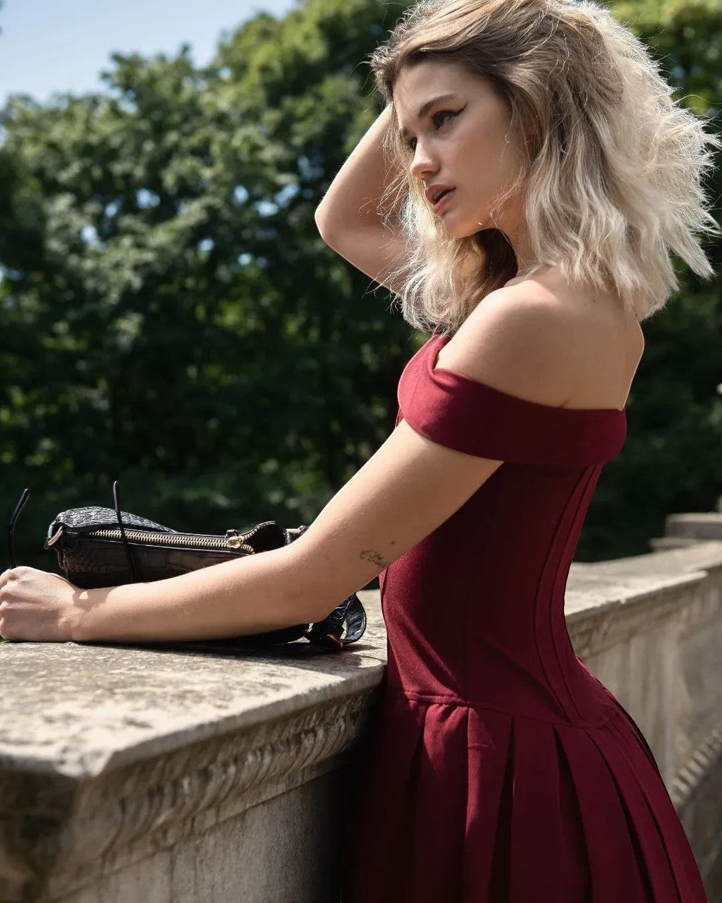 Refined Elegance burgundy corset mini dress in deep red with off-shoulder neckline and pleated skirt on a model.