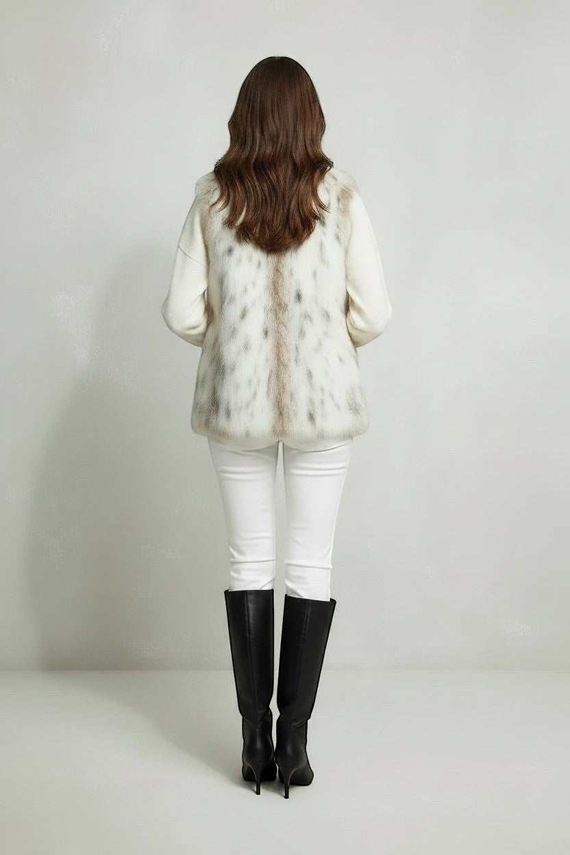Refined Elegance sleeveless faux fur vest in cream and taupe mottled pattern worn with white trousers and black boots